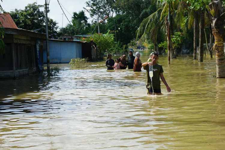 Aktivitas masyarakat saat banjir masih menggenangi Jalan Jalan Khairil Anwar, Kelurahan Pekan Tanjung Pura, Kecamatan Tanjung Pura, Kabupaten Langkat, Sumatera Utara pada Jumat (5/12/2025). 