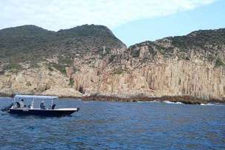 Kapal melintas di depan bukit yang tersusun dari bebatuan yang terbentuk sejak letusan gunung berapi 140 juta tahun lalu di Hongkong Geopark.