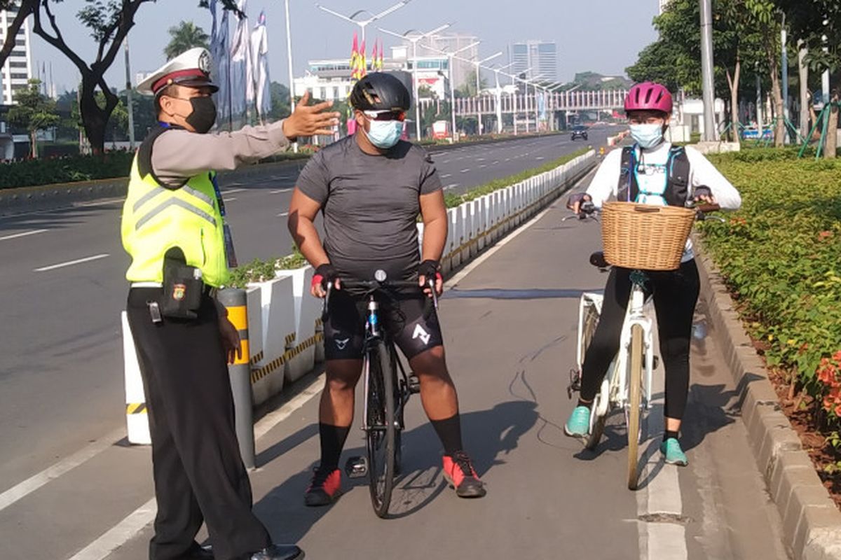 Polisi memberhentikan pesepeda di jalur sepeda permanen di Jalan Sudirman, Jakarta, pada hari pertama PPKM Darurat, Sabtu (3/7/2021).
