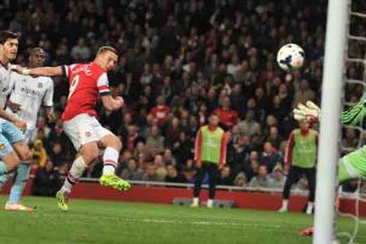 Striker Arsenal, Lukas Podolski (3 dari kiri), melepaskan tembakan yang menghasilkan gol ke gawang West Ham United pada laga Premier League di Emirates Stadium, Selasa (15/4/2014).
