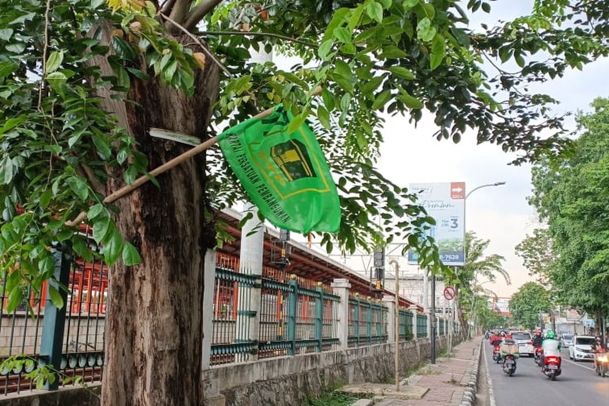 Atribut salah satu partai politik yang terpasang dengan cara dipaku di pohon tepat di depan Stasiun Bekasi, Marga Mulya, Kota Bekasi, Selasa (10/1/2023).