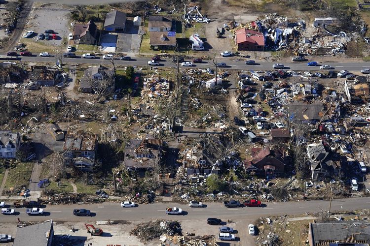 Dalam foto udara ini, mobil-mobil tengah melintas di wilayah dengan kondisi rumah-rumah yang hancur akibat tornado yang melanda wilayah Mayfield, Ky., Minggu (12/12/2021).