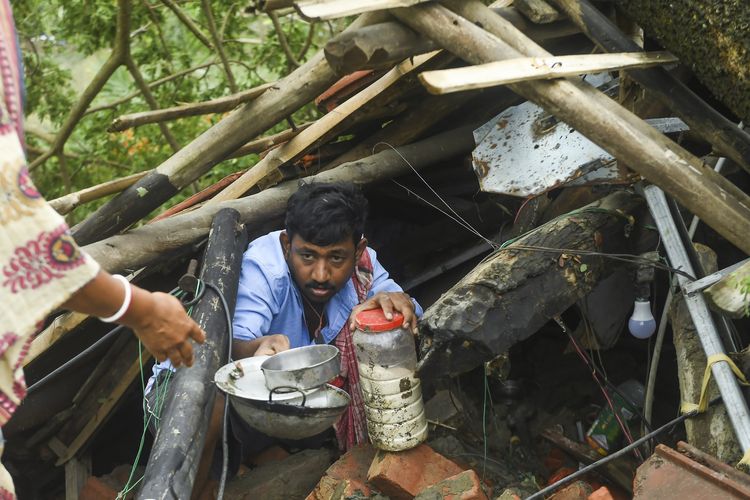 Seorang warga menyelamatkan barang dari rumah mereka yang rusak akibat Topan Amphan di Midnapore, West Bengal, India, pada 21 Mei 2020. Topan Amphan adalah siklon terkuat dalam beberapa dekade terakhir yang menyerang Bangladesh dan timur India pada 20 Mei 2020.