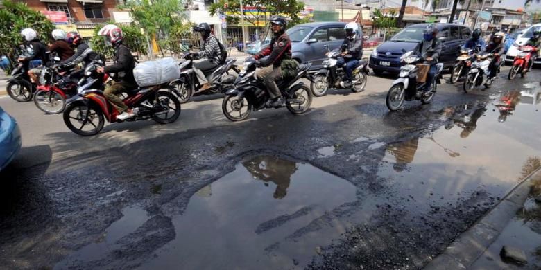 Pengendara motor menghindari kubangan air karena rusaknya aspal di Jalan Gunung Saharai, Jakarta, Senin (1/4/2013). Lubang di jalan yang tertutup genangan air sering membuat pengendara motor terperosok dan jatuh.