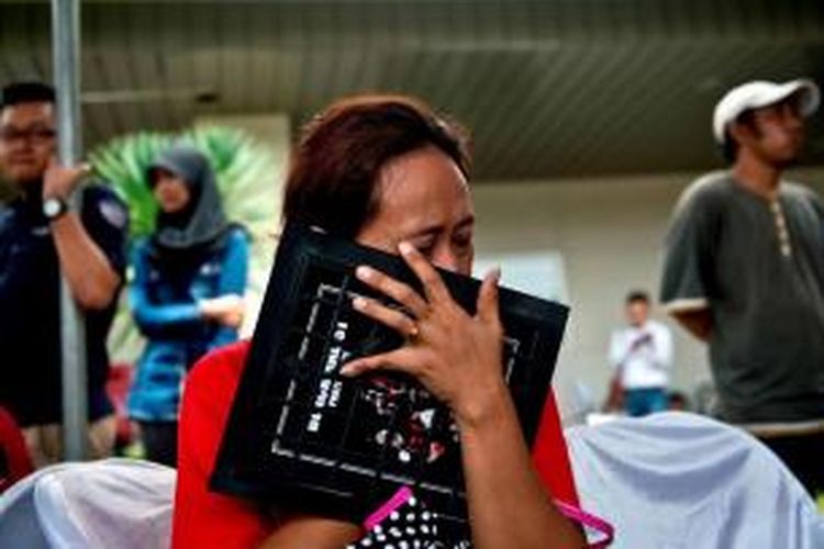Salah seorang keluarga korban hilangnya pesawat AirAsia QZ8501 memeluk foto saat berada di crisis-centre di Bandara Juanda, Surabaya, Senin (29/12/2014). Pesawat AirAsia QZ8501 yang mengangkut 155 penumpang serta 7 awak, hilang kontak pada Minggu pagi, saat penerbangan dari Surabaya menuju Singapura.