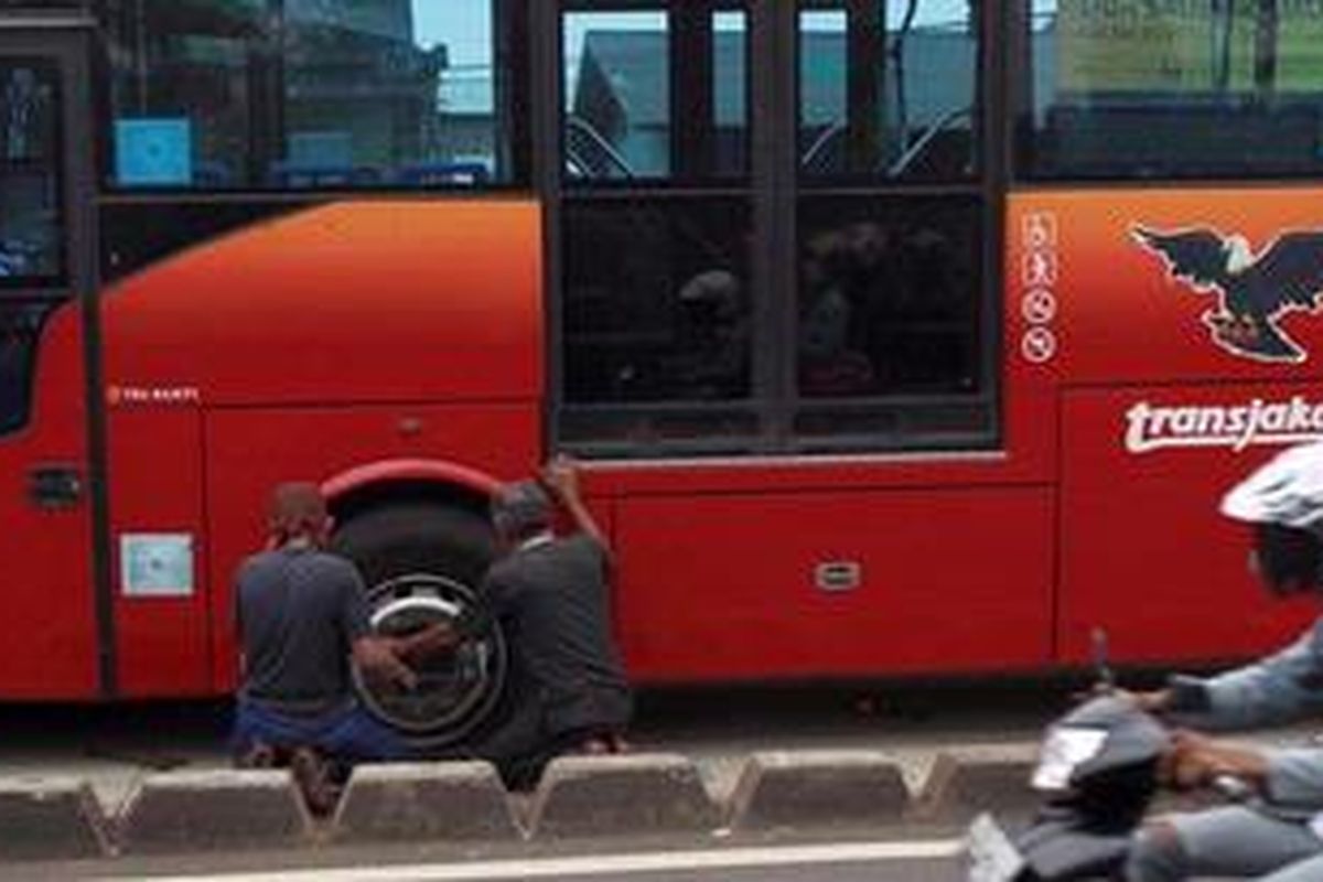Petugas membetulkan ban bus transjakarta yang digembosi warga terkait rencana penggusuran di Jalan I Gusti Ngurah Rai, Jakarta Timur, Sabtu (18/5/2013). Selain menggembosi tiga bus transjakarta koridor XI (Kampung Melayu - Pulogebang), warga juga memblokir jalan dengan membakar ban bekas.

