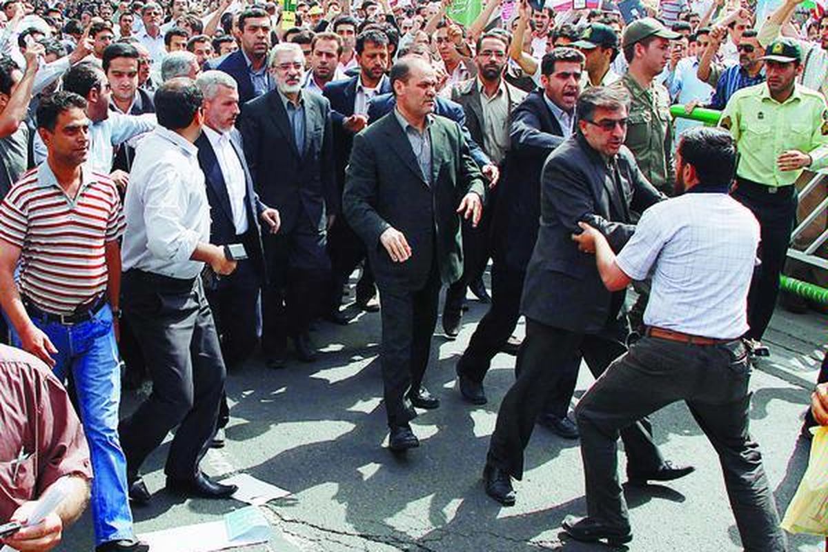 Mir Hossein Mousavi, tokoh oposisi berjambang putih (tengah), dilindungi pengawalnya saat menghadiri pawai Hari Quds di Teheran, Iran, Jumat (18/9). Seorang pendukung pemerintah, pria berbaju putih (kanan), berusaha mendekati Mousavi untuk menyerangnya.