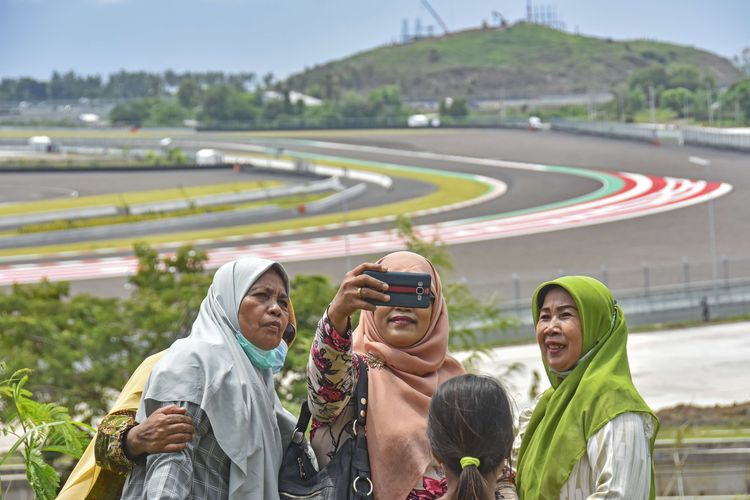 Sejumlah warga berswafoto saat menonton sesi tes pramusim MotoGP 2022 dari atas bukit sekitar Pertamina Mandalika International Street Circuit di KEK Mandalika, Desa Kuta, Kecamatan Pujut, Praya, Lombok Tengah, NTB, Sabtu (12/2/2022). Warga antusias menyaksikan tes pramusim MotoGP 2022 yang diikuti 24 pembalap di sirkuit yang memiliki panjang 4,32 km dengan 17 tikungan itu.