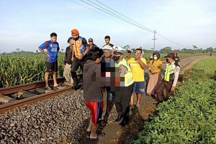Warga dan personel kepolisian menggotong tubuh Sugiati (36) usai tertabrak kereta api di Kelurahan Tangkil, Kecamatan Wlingi, Kabupaten Blitar, Senin (14/11/2022)
