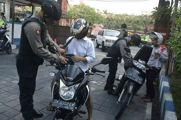 Petugas kepolisian memeriksa pengendara kendaraan bermotor di pintu masuk Mapolda Bali, Denpasar, Senin (14/5/2018). Petugas memperketat penjagaan kawasan Markas Polda Bali pascaledakan bom di sejumlah titik di Surabaya.