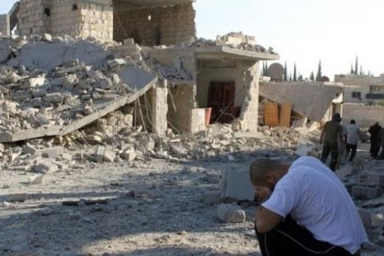 Seorang pria yang kehilangan anggota keluarganya menangis sambil duduk di depan rumahnya yang hancur akibat serangan udara pasukan rezim Suriah di desa Maaret al-Numan, Provinsi Idlib.