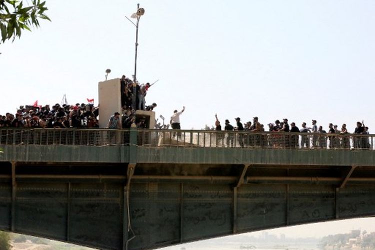 Pendukung ulama Irak Moqtada Sadr bersorak ketika yang lain meruntuhkan penghalang beton di sepanjang jembatan Al-Jumhuriya (Republik) yang mengarah ke Zona Hijau keamanan tinggi ibukota Baghdad, selama protes terhadap pencalonan blok saingan untuk perdana menteri, pada 30 Juli , 2022. 