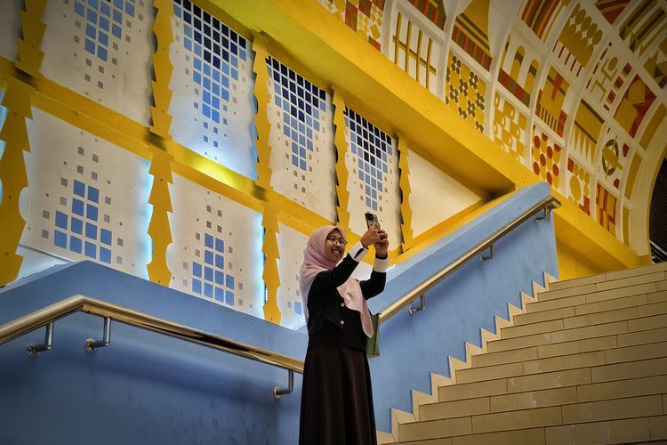 Potret pengunjung sedang berswafoto di lorong mal Blok M yang dihiasi latar motif mozaik, Jakarta Selatan, Senin (30/6/2025). 