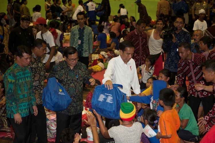 Presiden Joko Widodo (ketiga kiri) bersama Bupati Klungkung I Nyoman Suwirta (kiri) dan Sekretaris Kabinet Pramono Anung (kedua kiri) memberi bantuan kepada para pengungsi Gunung Agung di GOR Suwecapura, Klungkung, Bali, Selasa (26/9). Gunung Agung masih berstatus awas sehingga sampai saat ini sebanyak 75.673 warga yang bermukin di kawasan rawan bencana diungsikan di 377 tempat penampungan. 