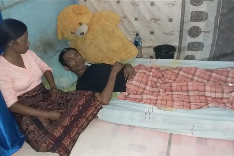 Foto : Ambrosius Roliyanto (34) saat terbaring di kamarnya ditemani sang isteri Barbara Adinda (32), di Kelurahan Wailiti, Kelurahan Alok Barat, Kabupaten Sikka, Flores, NTT, Jumat (12/7/2019). 
