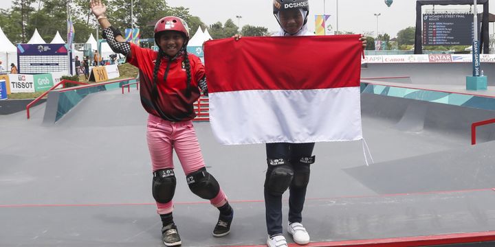 Skateboarder putri Indonesia Aliqqa Novvery (kiri) dan Bunga Nyimas (kanan) mengibarkan bendera merah putih usai mengikuti final skateboard kelas taman putri Asian Games 2018 di arena roller sport Jakabaring Sport City, Palembang, Sumatera Selatan, Rabu (29/8/2018).