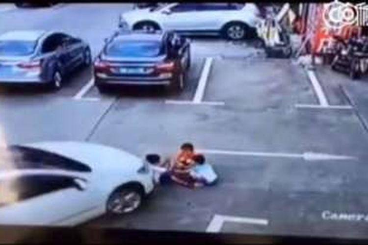 Gambar yang diambil dari rekaman CCTV memperlihatkan sebuah mobil sedan putih bergerak ke arah sekumpulan anak yang tengah bermain.