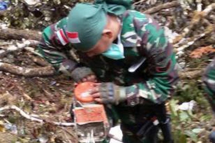 Foto yang dirilis oleh Kodam XVII/ Cendrawasih, 18 Agustus 2015, memperlihatkan seorang tentara menyelamatkan kotak hitam atau flight data recorder di antara puing pecahan pesawat Trigana Air ATR 42-300 yang jatuh di kawasan pegunungan di Oksibil, Papua.