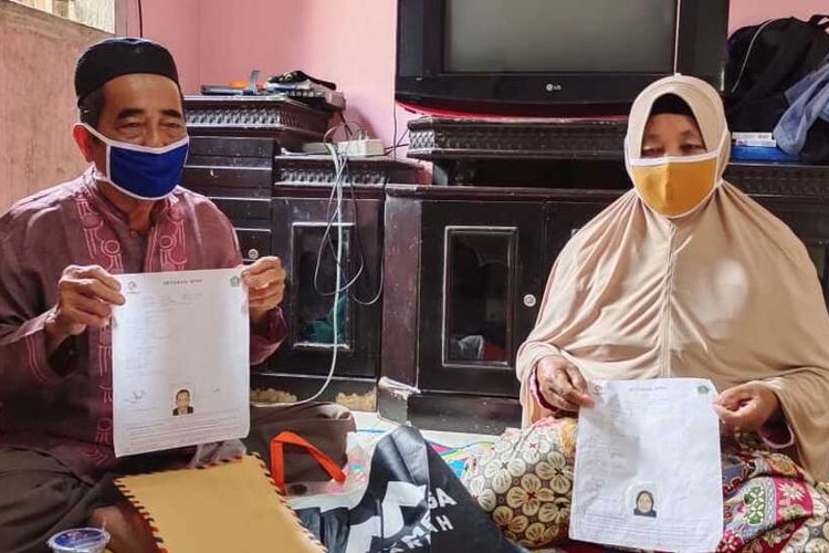 Buhotim (70) dan istrinya Nurhiyas (58) memperlihatkan bukti pelunasan biaya haji saat ditemui Kompas.com di rumahnya di Desa Terantang, Kecamatan Tambang, Kabupaten Kampar, Riau, Sabtu (5/6/2021).
