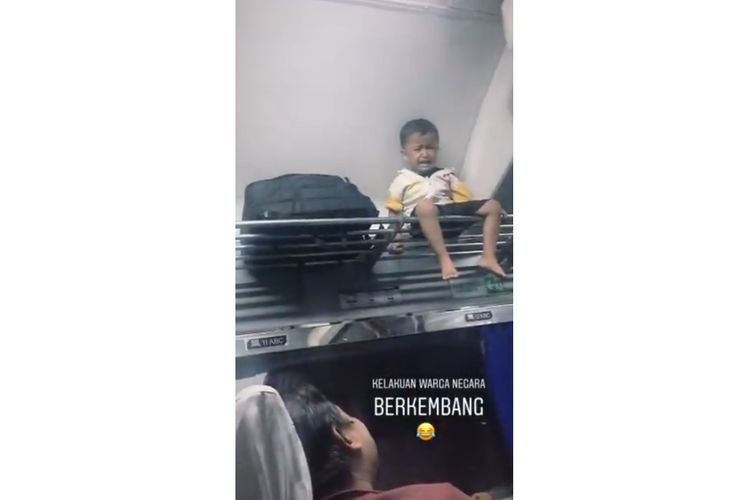 Tangkapan layar dari sebuah video viral mengenai anak kecil yang duduk di rak bagasi kereta api.