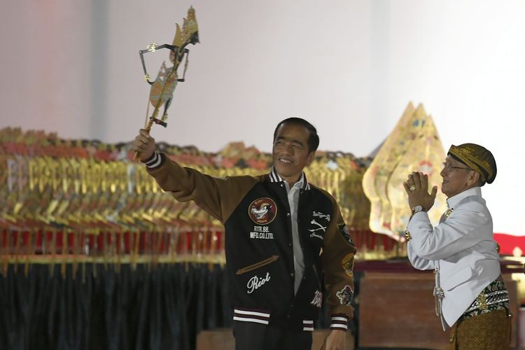 Presiden Joko Widodo (kiri) menerima wayang Kresna dari Dalang Ki Manteb Sudarsono (kanan) saat Pagelaran Wayang Kulit di halaman Istana Merdeka, Jakarta, Jumat (2/8/2019). Pagelaran wayang kulit dalam rangkaian ulang tahun Kemerdekaan Indonesia ke-74 dengan lakon Kresna Jumeneng Ratu.