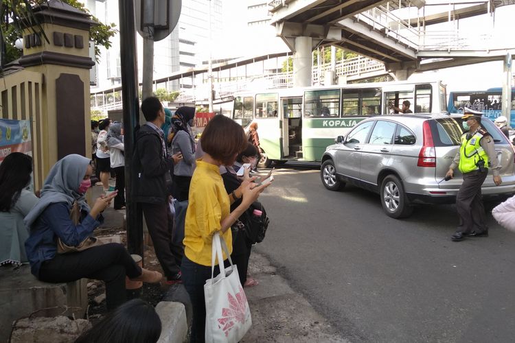 Penumpang Transjakarta keluar dari bus karena macet parah di Simpang Matraman, Selasa (10/4/2018)
