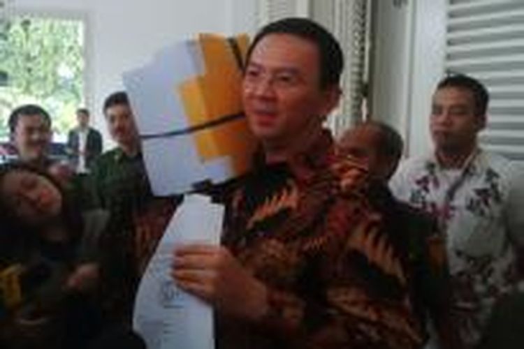 Gubernur DKI Jakarta Basuki Tjahaja Purnama memanggul tumpukan dokumen RAPBD 2015 hasil koreksi Kemendagri, di Balai Kota, Senin (23/3/2015). 