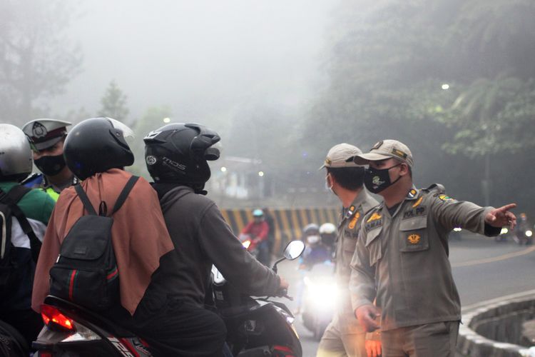 Petugas gabungan memutar balik kendaraan dari arah Bogor yang hendak menuju Cianjur di wilayah perbatasan Puncak Pass, Cianjur, Jawa Barat, Minggu (16/5/2021).