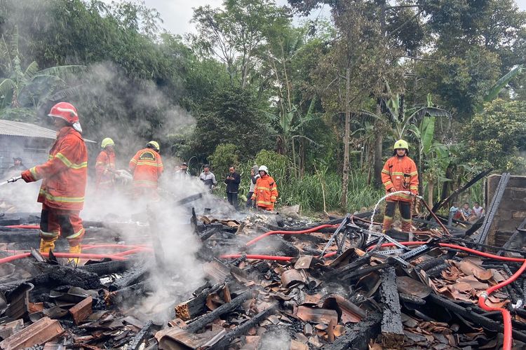 Petugas memadamkan api yang membakar rumah Sardimin