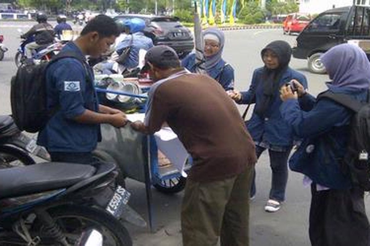 Pedagang dawet di Kota Semarang, Wuwuh, ikut tanda tangan di kertas petisi penolakan kenaikan harga BBM, yang disodorkan puluhan mahasiswa Undip, Semarang, Jumat (9/3/2012), seusai mahasiswa unjuk rasa di kawasan Tugu Muda, Semarang, Jawa Tengah.