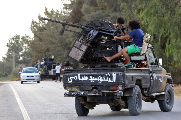 Anggota milisi yang setia pada pemerintah nasional bersiap di atas kendaraan yang dipasangi senjata berat, di Tripoli.