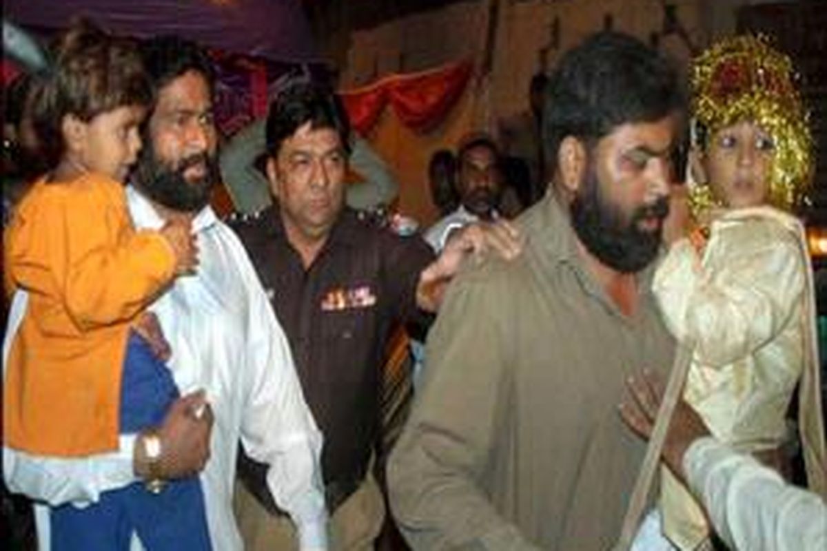 Polisi mengendong 2 anak yang dinikahkan dalam suatu acara yang dihadiri oleh 100 tamu. Kedua anak itu adalah pengantin perempuan (kiri) yang masih berusia 4 tahun dan pengantin pria yang masih berusia 7 tahun