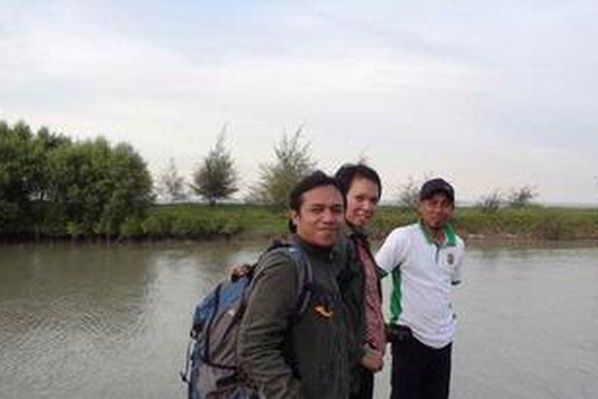 Sutrisno (baju putih) dan pengunjung kawasan wisata mangrove Sungai Nipah dengan latar belakang hutan bakau dan laut.