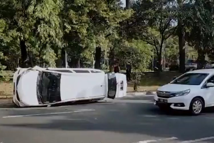 Minibus berwarna putih berpelat nomor polisi T 1312 HB, terbalik di Jalan Raya Margonda, Depok pada Sabtu (23/7/2022) pagi tadi. Tak ada korban jiwa maupun luka-luka atas kecelakaan tersebut. (Istimewa/tangkapan layar video)