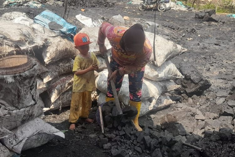 Pekerja tambang batubara membawa anaknya untuk bekerja mengarungi batubara di tambang rakyat, Desa Darmo, Kecamatan Lawang Kidul, Kabupaten Muara Enim, Provinsi Sumatera Selatan 