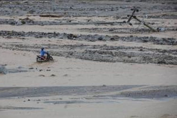 Warga menyeberangi Kali Sambong yang terkena aliran lahar hujan Gunung Kelud, 19 Februari 2014. Banjir lahar yang membawa material lumpur dan bebatuan ini memutuskan akses dari Waduk Selorejo, Desa Pandansari ke Dusun Klangon dan Kedawun, Kecamatan Ngantang, Kabupaten Malang.