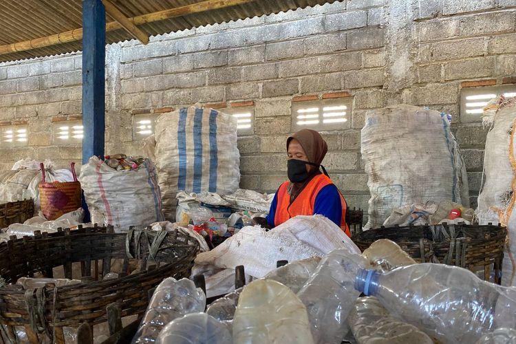 Seorang ibu tengah melakukan pembersihan label dan tutup dari sampah botol plastik air minum kemasan di Bangoan Collection Center, Tulungagung, Selasa (19/7/2022). Lokasi ini menjadi salah satu penyuplai sampah botol plastik air minum kemasan sebelum dibawa ke  PT. Veolia Services Indonesia, Pasuruan untuk diubah menjadi pellet plastik.