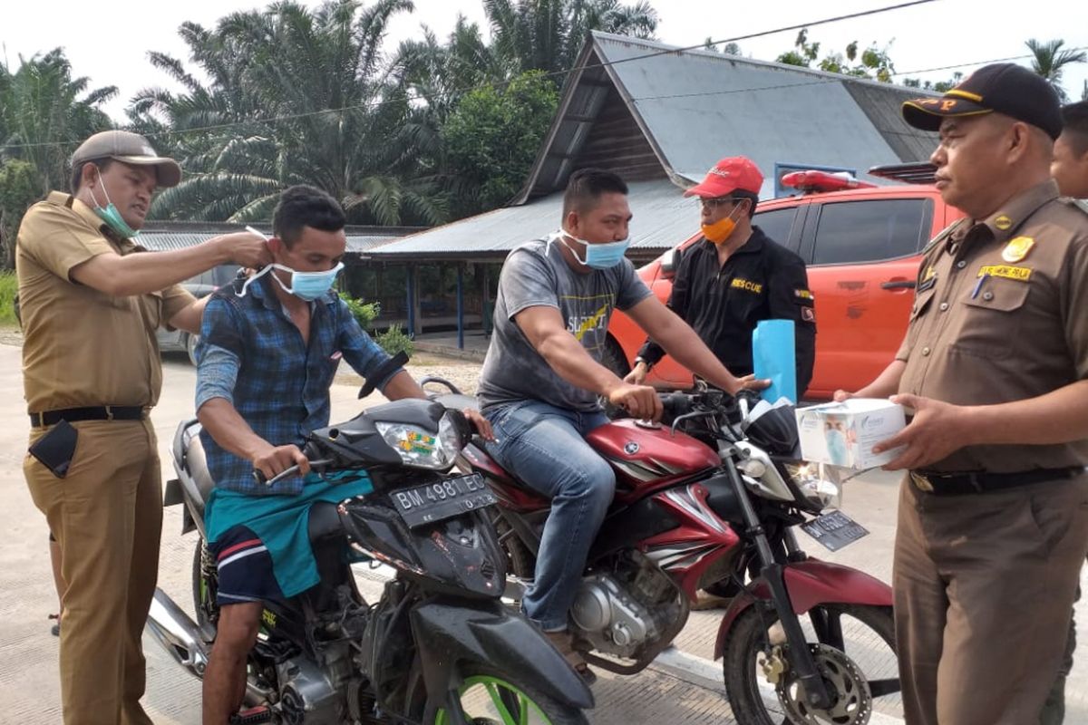 Camat Rupat Hanafi (kiri) dan Kepala BPBD Kabupaten Bengkalis Tajul Mudaris (topi merah) membagikan masker ke masyarakat untuk mengantisipasi dampak kabut asap di wilayah Kecamatan Rupat, Kabupaten Bengkalis, Riau, Senin (25/2/2019).