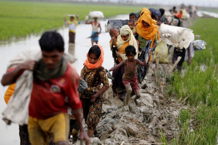 Pengungsi Rohingya berjalan di jalan berlumpur setelah menyebrangi perbatasan Bangladesh-Myanmar di Teknaf, Bangladesh, Minggu (3/9/2017).