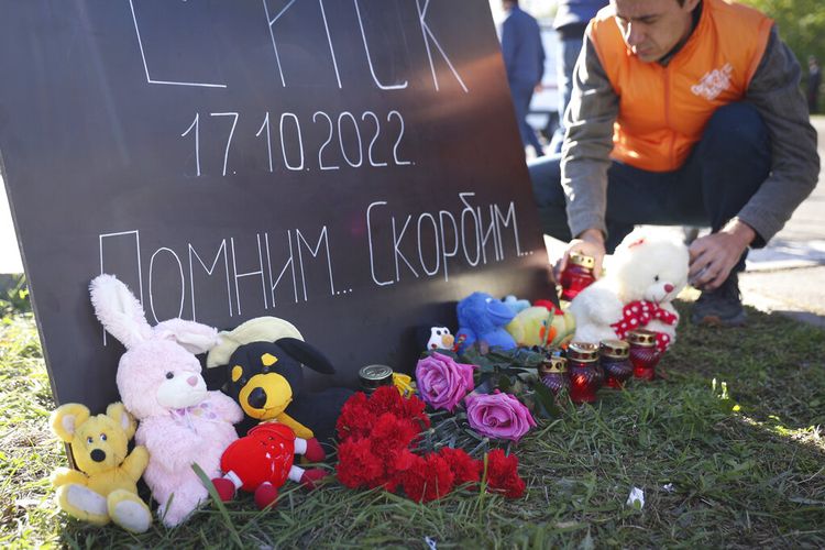 Orang-orang membawa bunga dan mainan ke poster yang bertuliskan 'Yeysk' dalam bahasa Rusia. Kita ingat. Kami berduka', di dekat lokasi kecelakaan pesawat di daerah perumahan di Yeysk, Rusia, Selasa, 18 Oktober 2022.