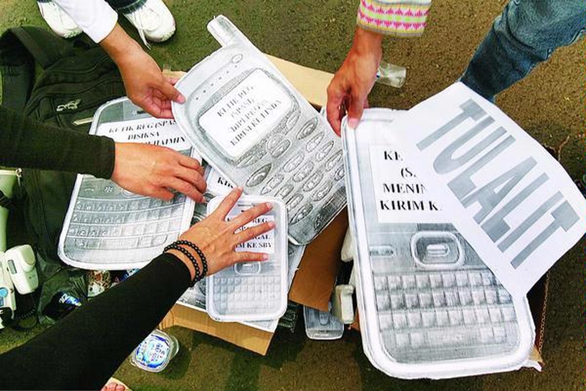 Lembaga swadaya masyarakat Migrant Care berunjuk rasa dengan membawa model telepon seluler raksasa untuk menentang rencana kebijakan pemberian telepon seluler kepada buruh migran di depan Istana Negara, Jakarta, Jumat (26/11). Pemerintah Indonesia diminta memasukkan hak informasi dan komunikasi bagi buruh migran dalam nota kesepahaman atau perjanjian bilateral dengan negara-negara tujuan buruh migran.