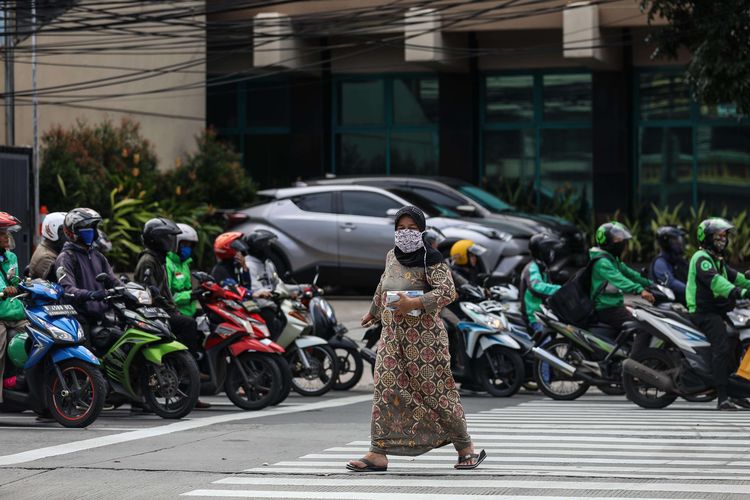 Warga menggunakan masker saat melintasi jalan di kawasan Mampang Prapatan, Jakarta Selatan, Senin (6/4/2020). Kebijakan wajib masker itu  tertuang dalam Seruan Gubernur Daerah Khusus Ibu Kota Jakarta Nomor 9 Tahun 2020 Tentang Penggunaan Masker Untuk Mencegah Penularan Corona Virus Disease (Covid-19).