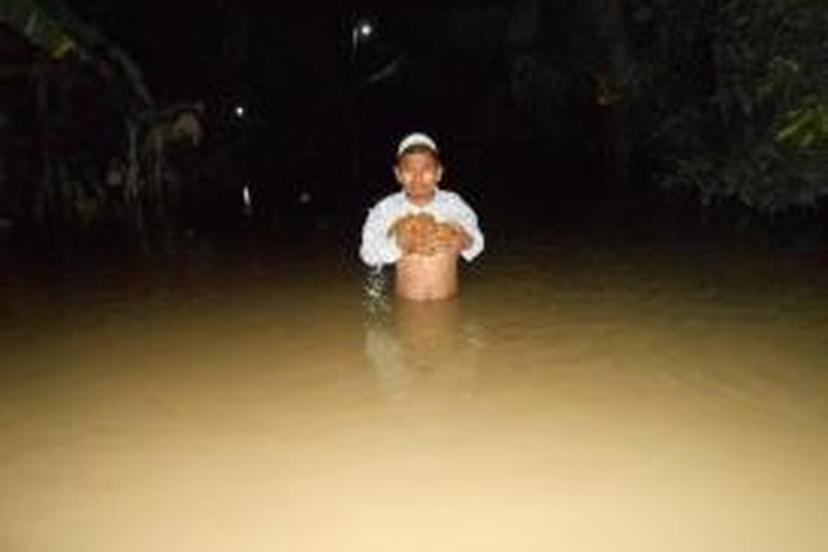 Seorang warga nekat menerobos jalan di Dukuh Kalitageh Desa Ploso Kecamatan Karangtengah, Demak, yang tergenang air sepinggang orang dewasa, Senin malam (23/12/2013) 