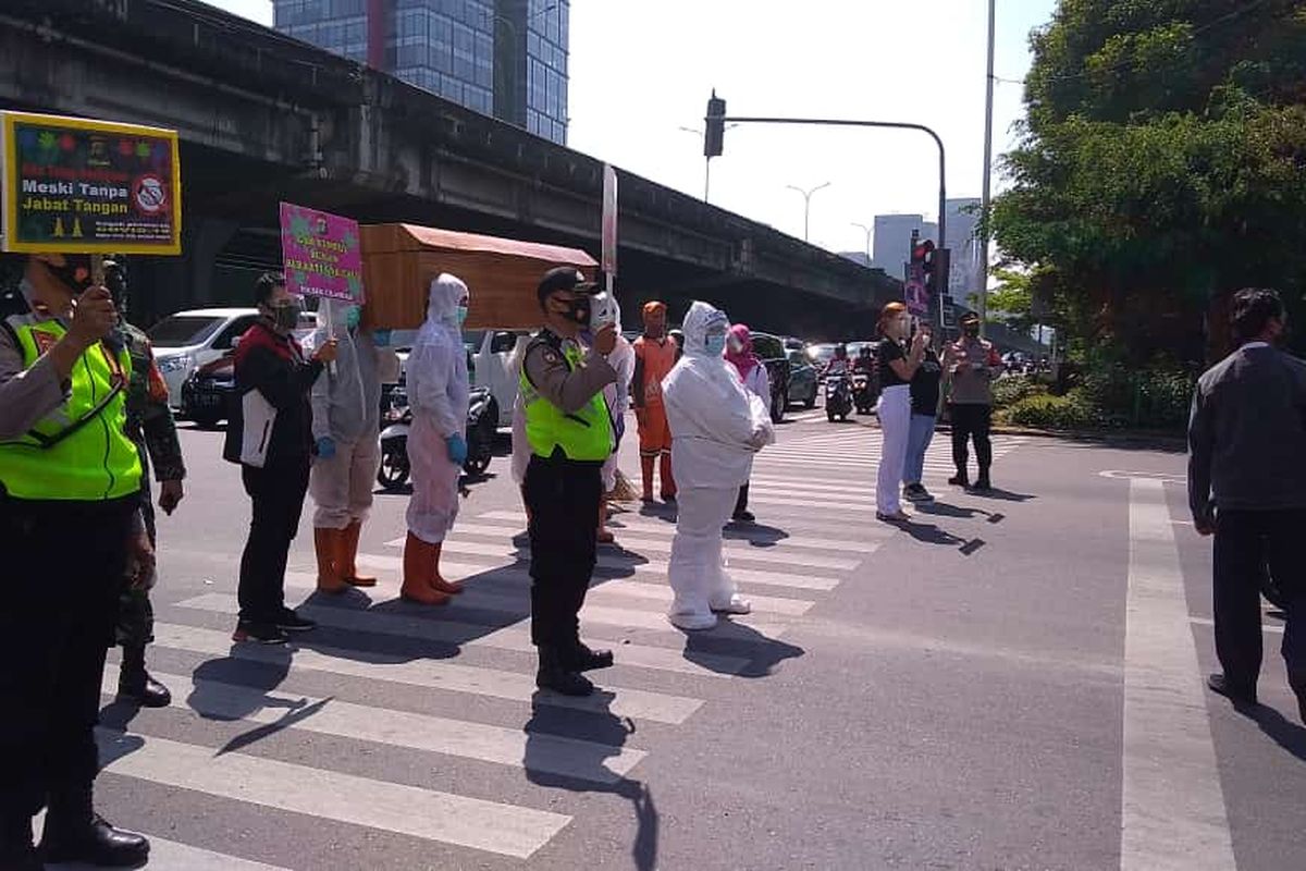 Sejumlah unsur gabungan menggunakan benda berbentuk peti mati untuk mengingatkan bahaya penularan Covid-19 di perempatan Jalan Raya Fatmawati, Cilandak, Jakarta, Rabu (26/8/2020) pagi.