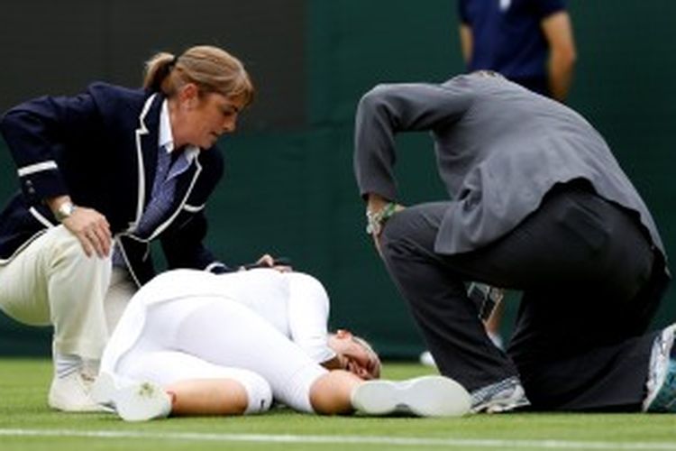 Petenis Belarusia, Victoria Azarenka (tengah), menangis setelah terjatuh pada set kedua babak pertama Wimbledon, saat menghadapi Maria Joao Koehler dari Portugal. Azarenka menang 6-1 6-2.