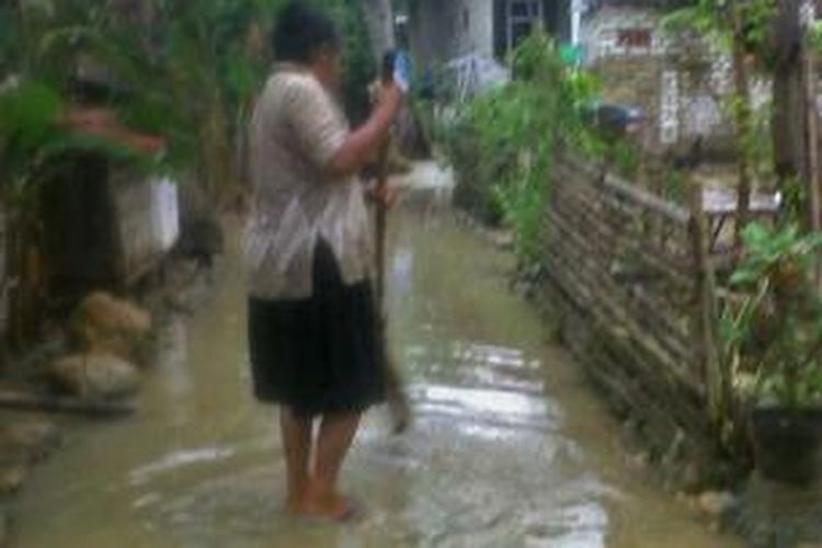 Warga Desa Laden, Kecamatan Pamekasan Pamekasan, bersih-bersih halaman rumahnya setelah terkena banjir semalam. 