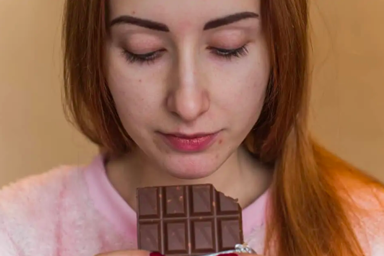 Ilustrasi wanita makan cokelat hitam untuk mengurangi stres. Cokelat hitam adalah salah satu makanan pilihan yang bisa meredakan stres.