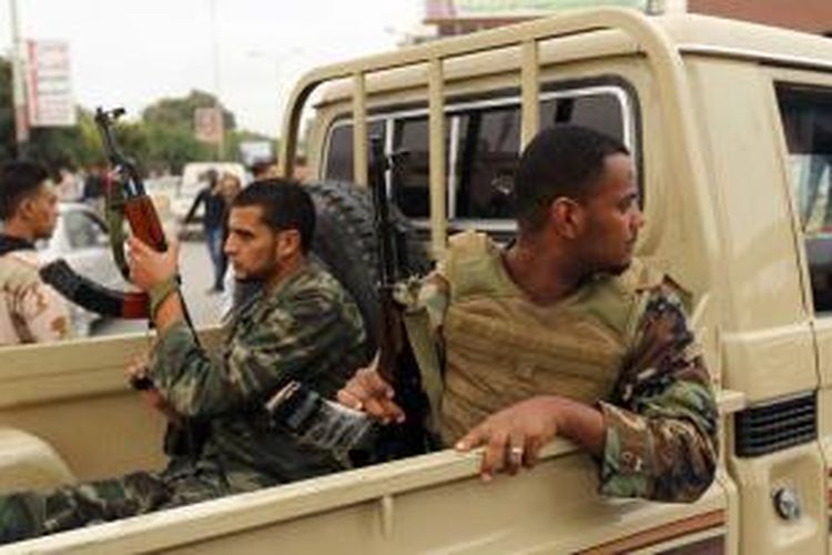 Dua orang prajurit angkatan darat Libya duduk di sebuah mobil bak terbuka di kota Benghazi yang dalam beberapa hari terakhir tegang karena bentrokan antara militer dan kelompok militan.