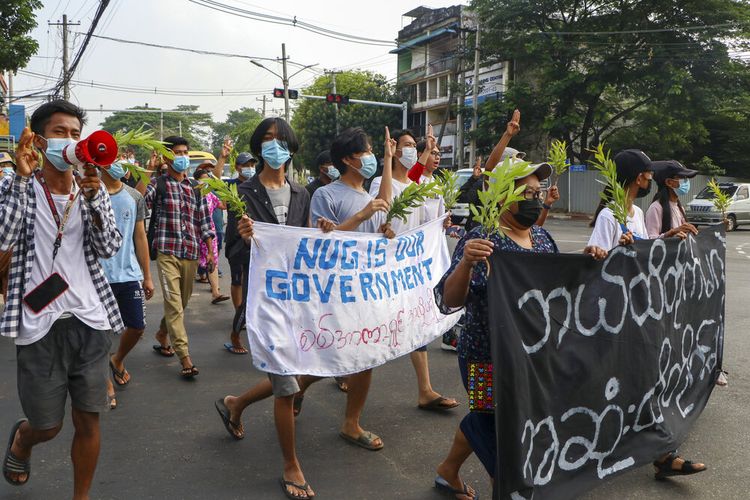 Pengunjuk rasa anti-kudeta menunjukkan hormat tiga jari, memegang spanduk selama demonstrasi menentang kudeta militer di Yangon, Myanmar, Senin, (26/4/2021).
