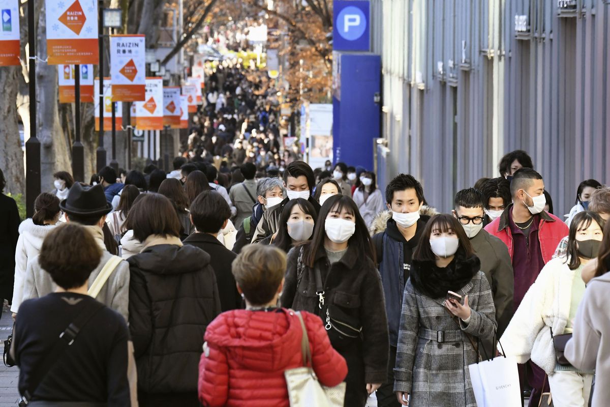 People wearing face masks to help curb the spread of the coronavirus walk on Aoyama shopping street in Tokyo Sunday, Dec. 27, 2020. Japan is barring entry of all nonresident foreign nationals as a precaution against a new and potentially more contagious coronavirus variant that has spread across Britain. The Foreign Ministry says the entry ban will start Monday and last through Jan. 31. (Yuka Ando/Kyodo News via AP)